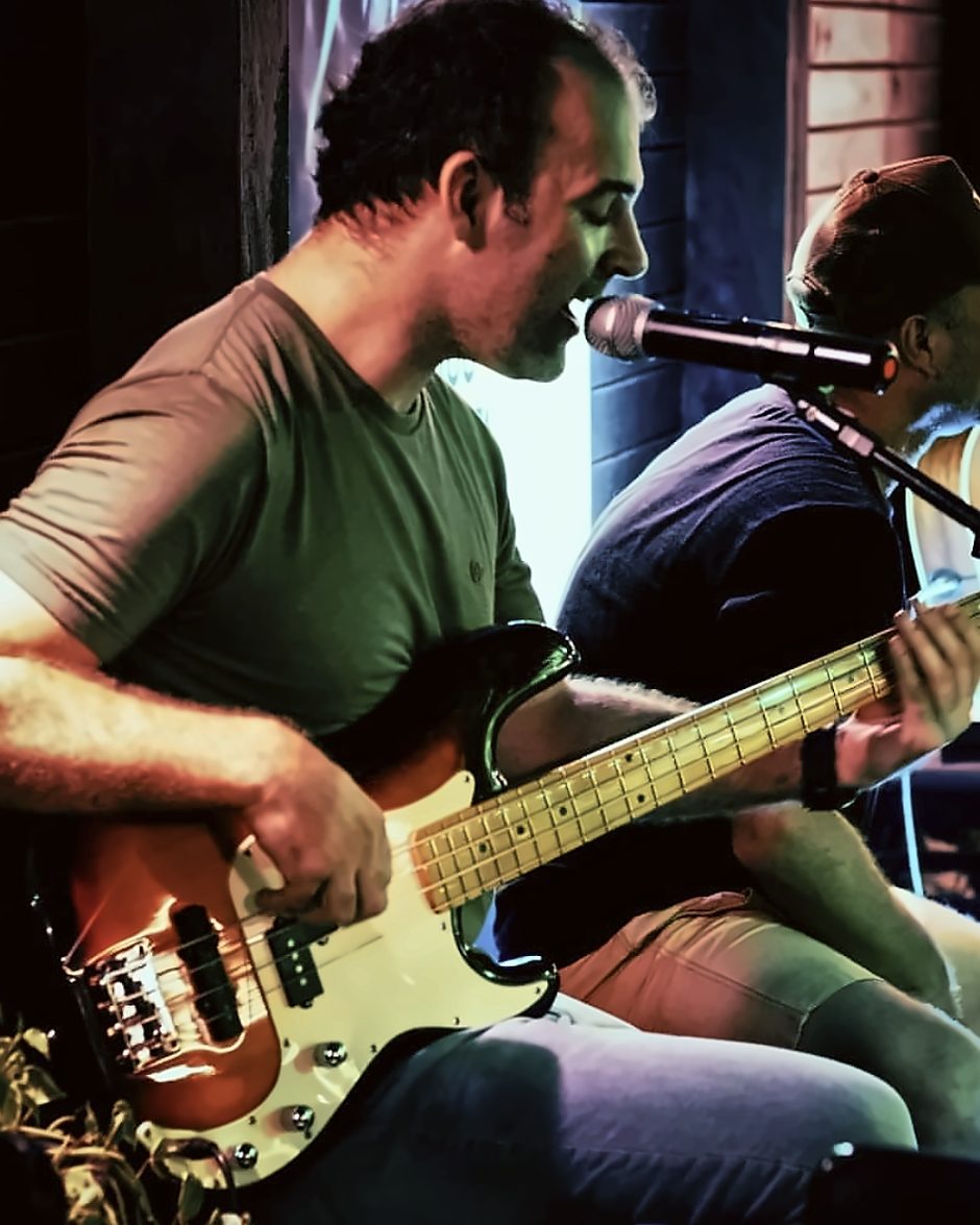 Alexandre cantando ao microfone enquanto toca contrabaixo