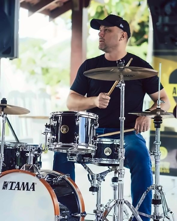 Robson tocando bateria sob um quiosque de madeira